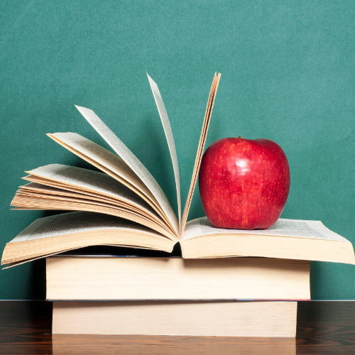 Red Apple placed on stack of books with green background